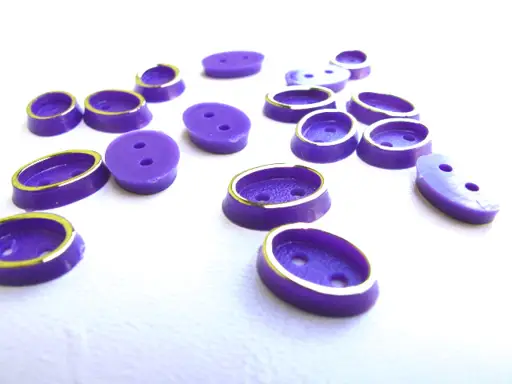 Gombík dvojdierkový košeľový oválik 7x10mmx 10ks/zlato- fialový purpur